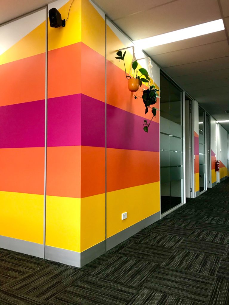 An office hallway featuring bright yellow, orange, and pink striped walls